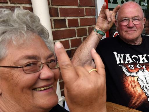 Die Anwohner Gerda und Karl-Heinz begrüssen in Wacken die anreisenden Heavy-Metal-Fans mit dem "Pommesgabel-Zeichen".