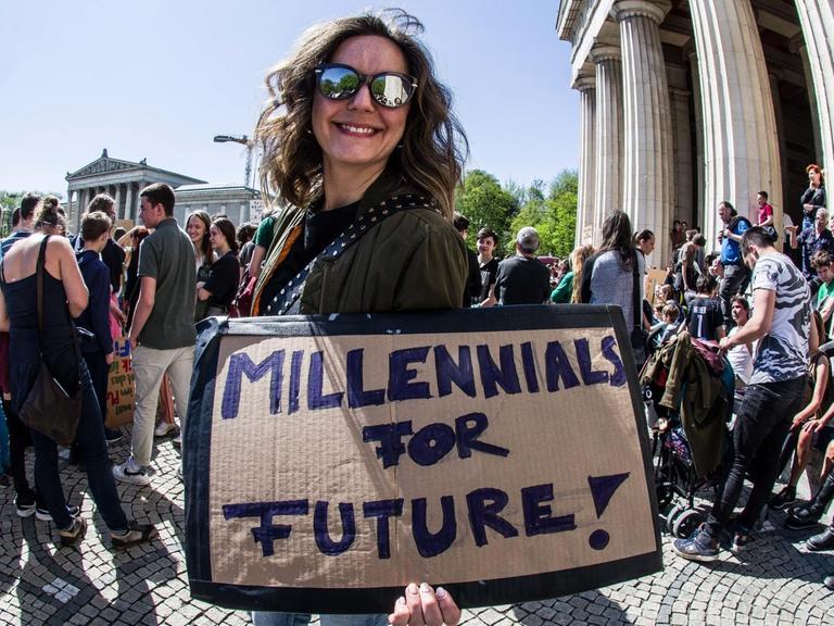Eine Demonstrantin in München hält am Karfreitag ein Schild mit der Aufschrift "Millennials for Future" in die Kamera.