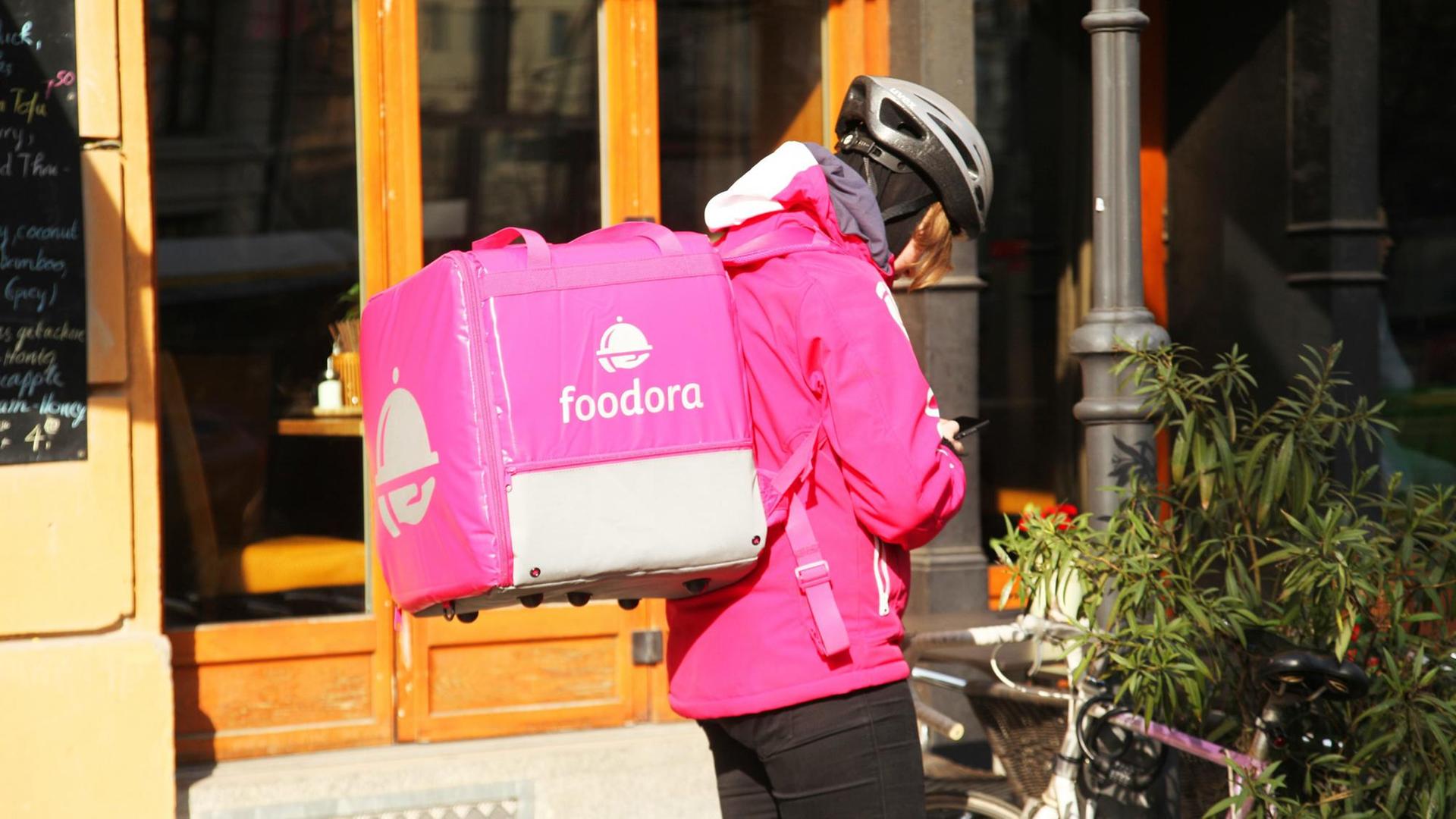Eine Fahrerin von Foodora steht in Berlin im Bezirk Mitte an ihrem Fahrrad. Eine Fahrerin von Foodora steht in Berlin im Bezirk Mitte an ihrem Fahrrad.