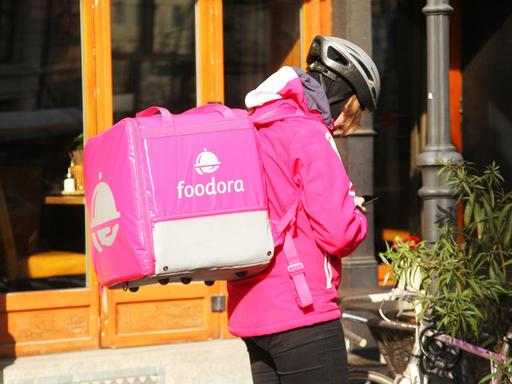Eine Fahrerin von Foodora steht in Berlin im Bezirk Mitte an ihrem Fahrrad.