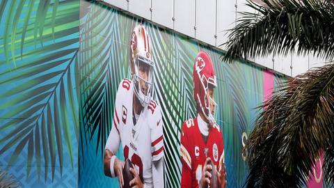 Blick auf eine Wand im Bayfront Park in Miami auf der zwischen Palmen die Quarterbacks der Kansas City Chiefs und der San Francisco 49ers abgebildet sind.