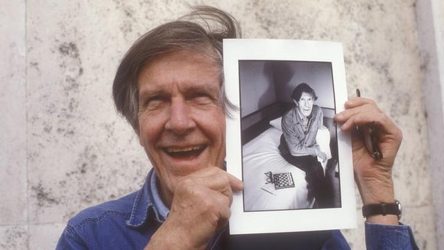 Der US-amerikanische Komponist John Cage (1912 – 1992) zeigt ein Foto von sich aus den frühen 80er-Jahren