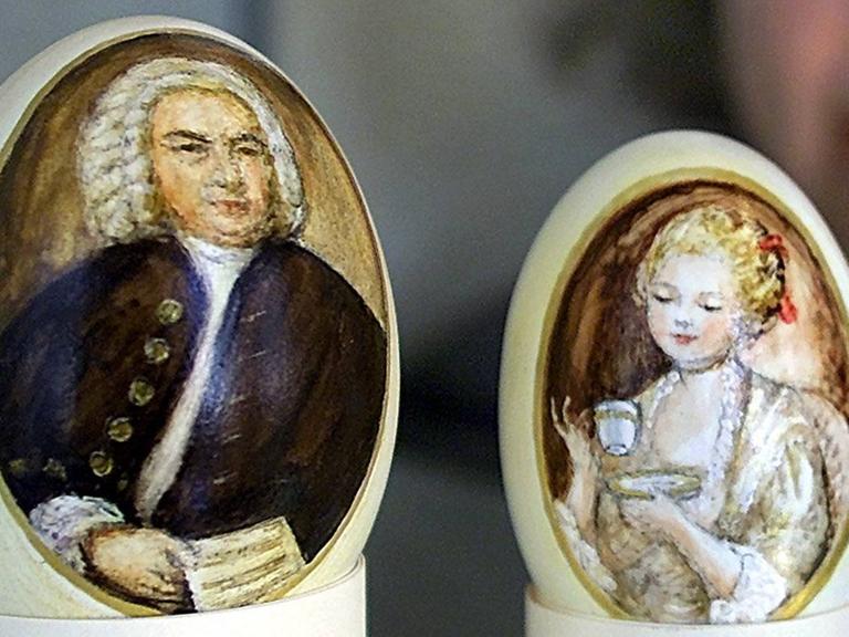 Eier mit handgemalten Portraits von Johann Sebastian Bach und des Liessgen aus der Kaffekantate, die eine Kaffeetasse vornehm vor sich hält.