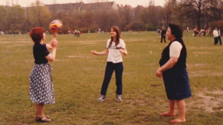 Drei Frauen werfen sich im Park einen Ball zu. Drei Frauen werfen sich im Park einen Ball zu.