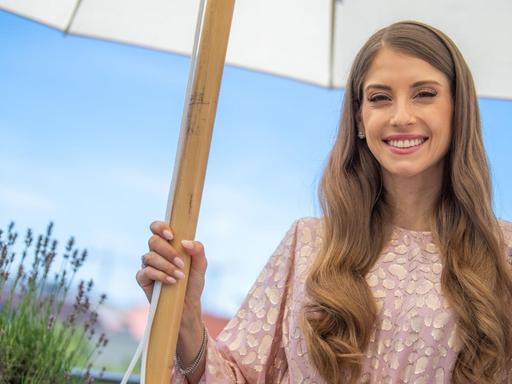 Cathy Hummels, Influencerin und Moderatorin, steht unter einem Sonnenschirm.