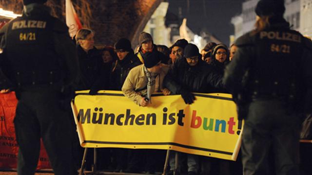 Ein Plakat mit der Aufschrift "München ist bunt", davor Polizisten