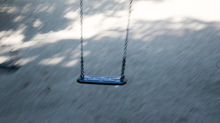 Eine schwingende Kinderschaukel auf einem öffentlichen Spielplatz in Bewegungsunschärfe