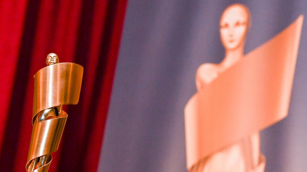 Die Gewinner-Statue beim deutschen Film-Preis ist eine goldene Figur, die von einem Film-Band umhüllt wird.