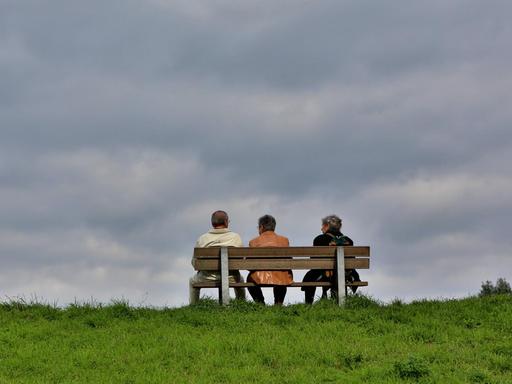 Ältere Menschen sitzen auf einer Bank.