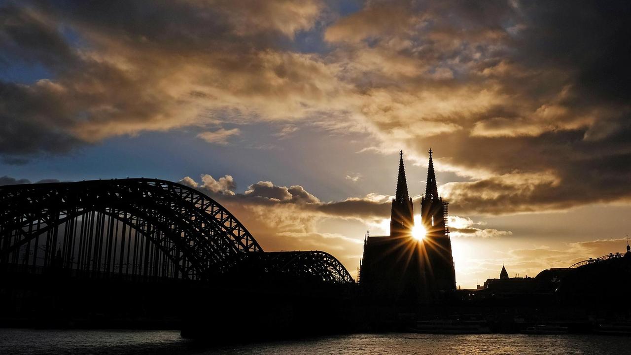 Wolken ziehen während Sonnenuntergangs über den Dom hinweg. Die Sonne ist zwischen den beiden Turmspitzen gerade noch so zu sehen. Wolken ziehen während Sonnenuntergangs über den Dom hinweg. Die Sonne ist zwischen den beiden Turmspitzen gerade noch so zu sehen.