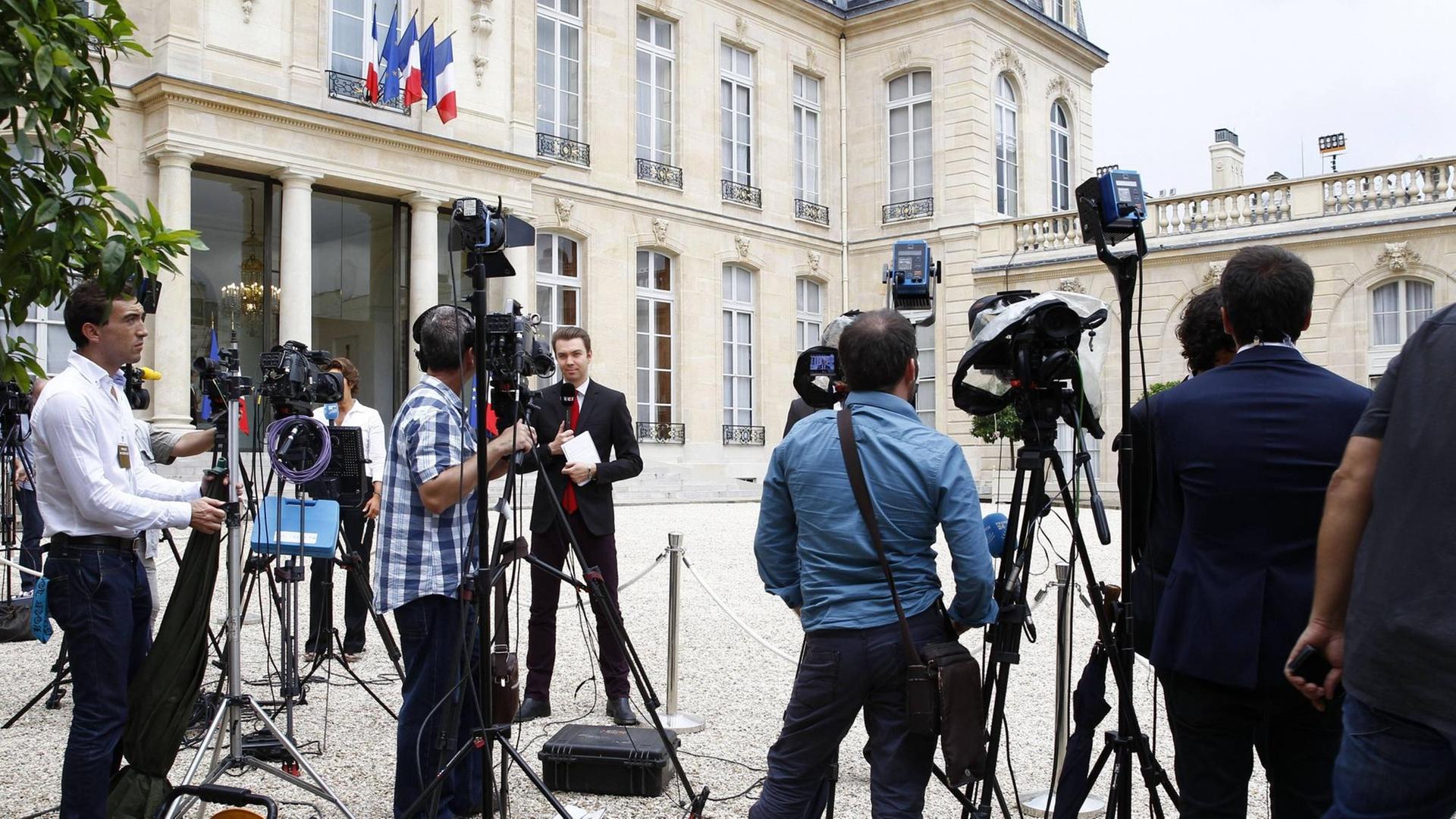 Journalisten stehen im Innenhof des Elysee-Palasts in Paris, Frankreich. Journalisten stehen im Innenhof des Elysee-Palasts in Paris, Frankreich.