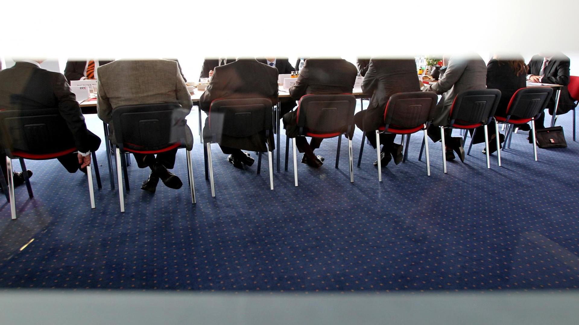 Eine Gruppe Männer mit Anzügen sitzen in einem Konferenzraum. Eine Gruppe Männer mit Anzügen sitzen in einem Konferenzraum.