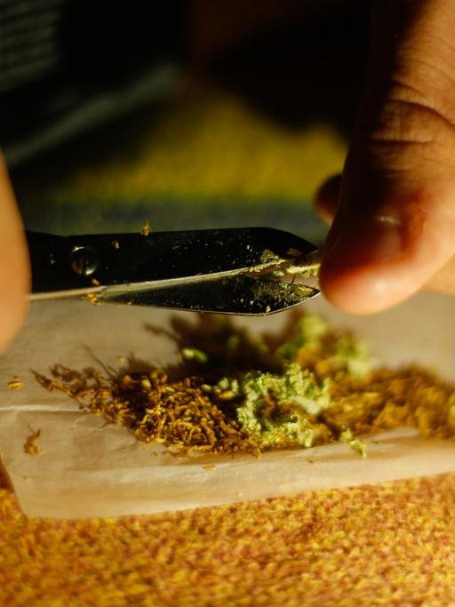 Ein Mann mischt Cannabis in einen Joint. 
