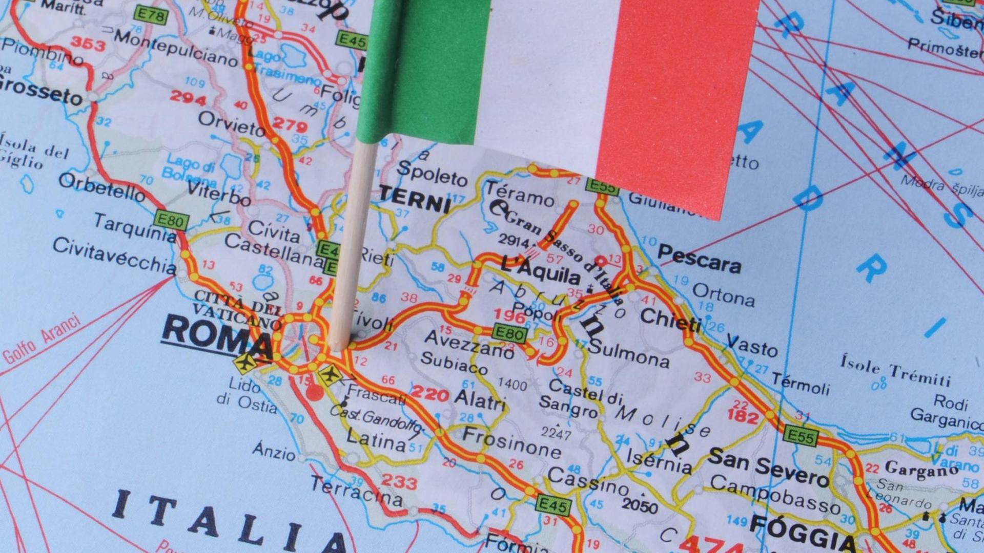 Eine kleine Italienflagge steckt in einer Landkarte Eine kleine Italienflagge steckt in einer Landkarte