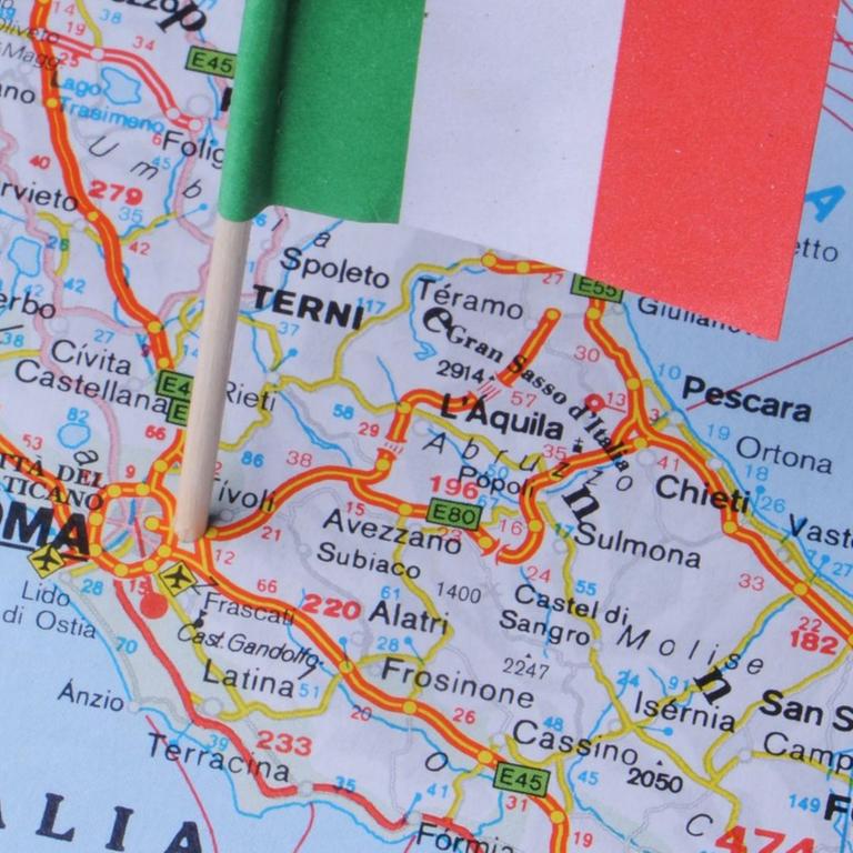 Eine kleine Italienflagge steckt in einer Landkarte 