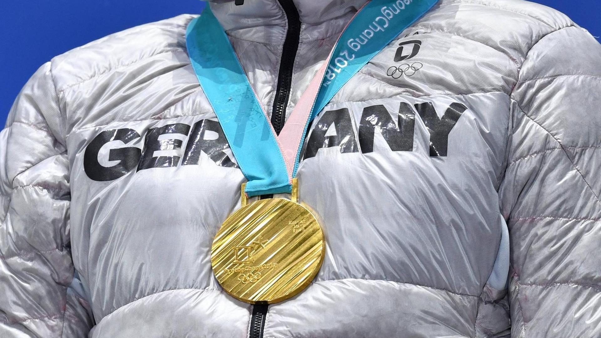 Arnd Peiffer mit Goldmedaille. Man sieht nur den Brustkorb und die Medaille. Arnd Peiffer mit Goldmedaille. Man sieht nur den Brustkorb und die Medaille.