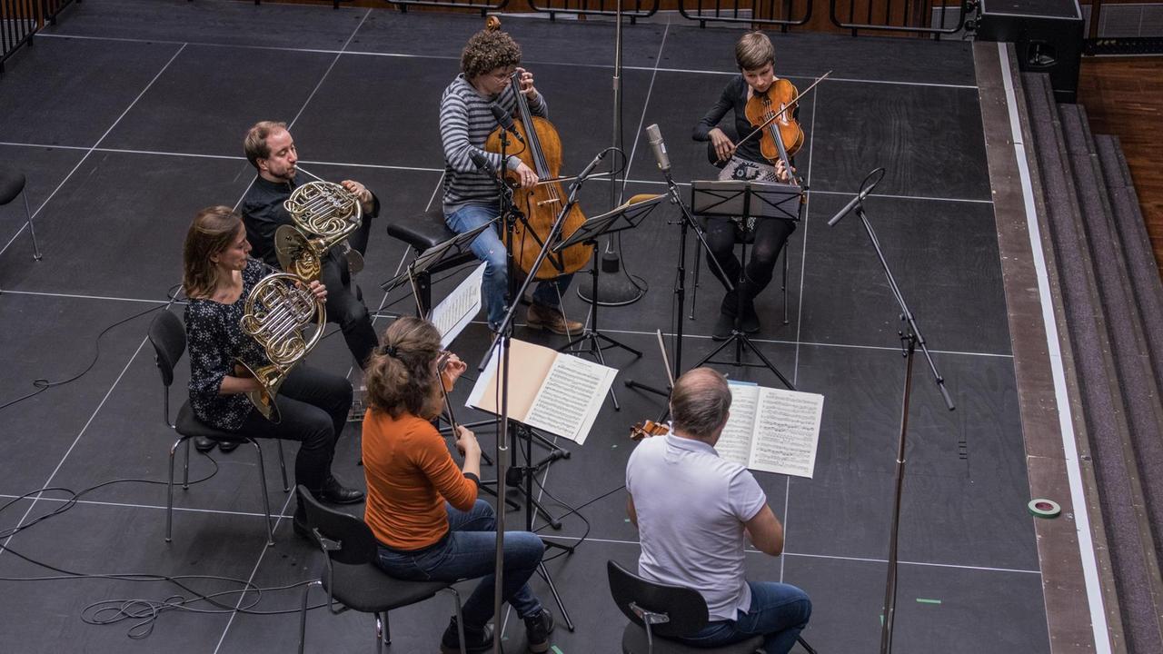 Blick von oben auf sechs Musikerinnen und Musiker, die auf der Bühne im Dlf Kammermusiksaal spielen Blick von oben auf sechs Musikerinnen und Musiker, die auf der Bühne im Dlf Kammermusiksaal spielen