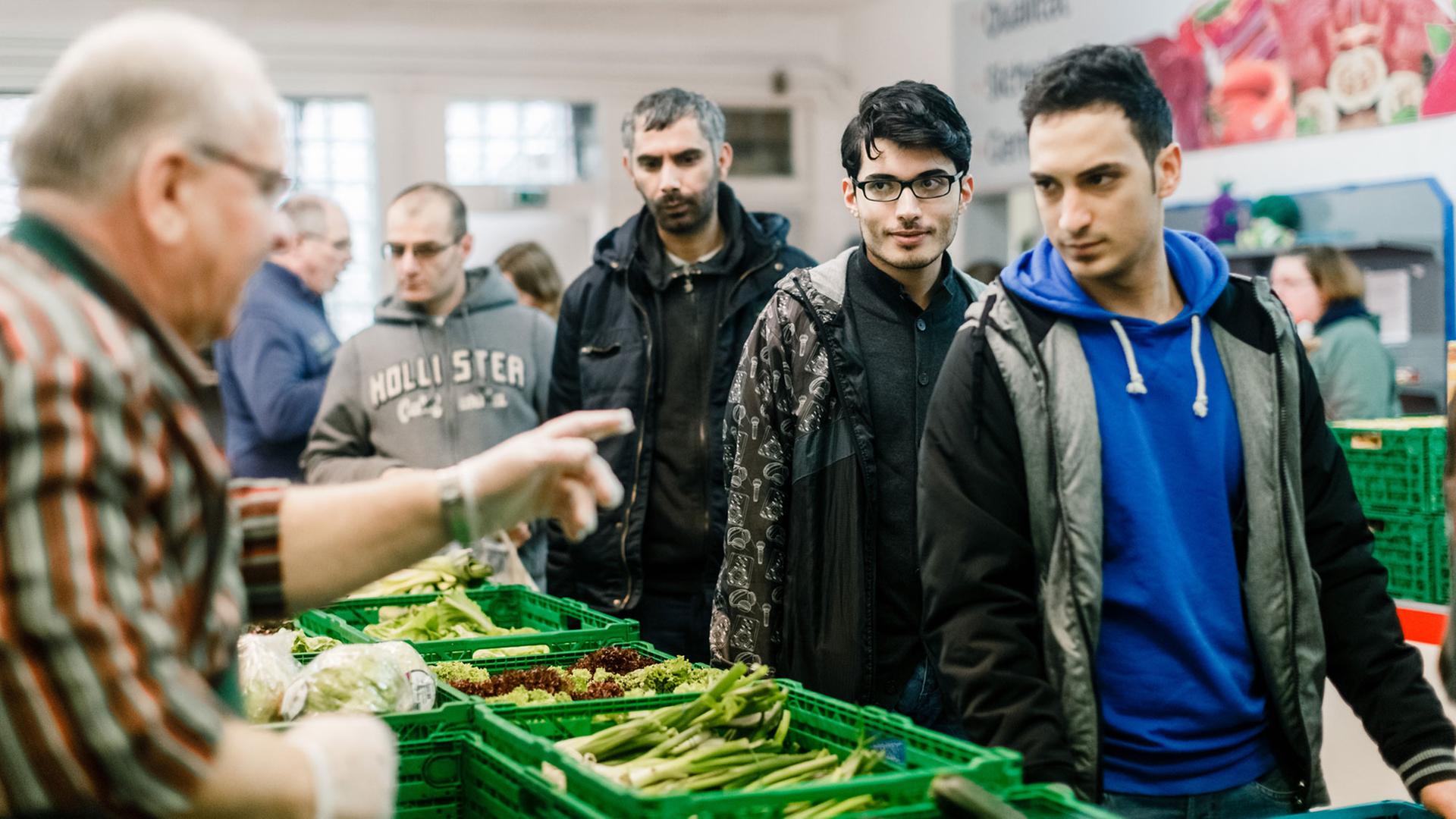 Ein ehrenamtlicher Mitarbeiter gibt am 30.12.2015 in Flensburg (Schleswig-Holstein) im Verteilraum der Flenburger Tafel Lebensmittel unter anderem an syrische Asylbewerber aus. Foto: Markus Scholz/dpa 