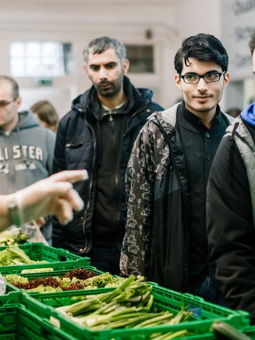 Ein ehrenamtlicher Mitarbeiter gibt am 30.12.2015 in Flensburg (Schleswig-Holstein) im Verteilraum der Flenburger Tafel Lebensmittel unter anderem an syrische Asylbewerber aus.