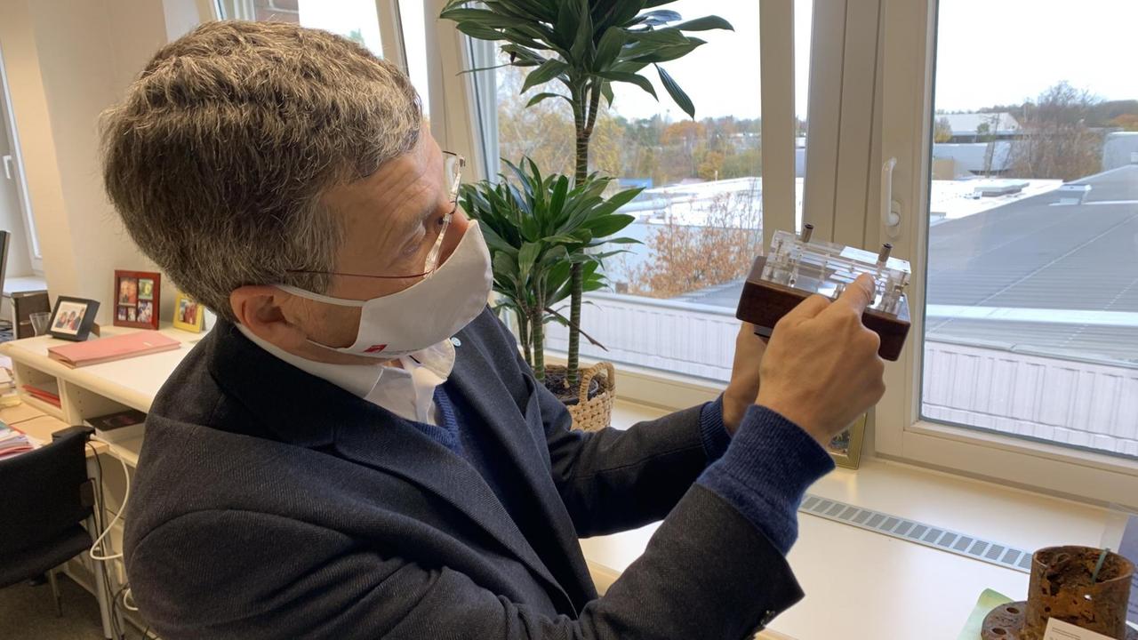 Wim Leemans hält die Plasmazelle aus durchsichtigem Saphir in der linken Hand und deutet auf den haarfeinen Kanal im Edelsteinblock Wim Leemans hält die Plasmazelle aus durchsichtigem Saphir in der linken Hand und deutet auf den haarfeinen Kanal im Edelsteinblock