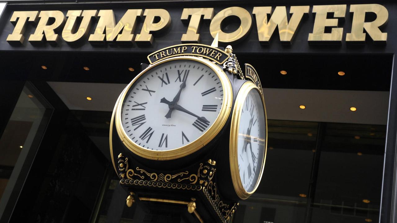Eine goldene Uhr vor dem goldenen Schriftzug am Trump Tower.
