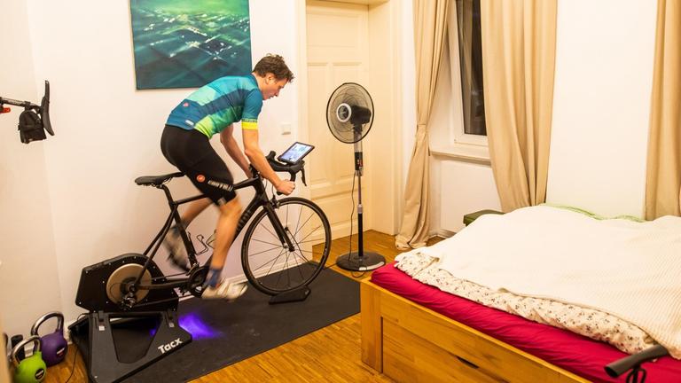 Amateur-Radsportler Nico Herzog trainiert auf dem Rollentrainer bzw. Heimtrainer in seinem Schlafzimmer. Er nutzt im Winter und während der derzeitigen Ausgangsbeschränkungen zur Unterstützung und Motivation eine Fahrrad-Simulations-App namens Zwift.