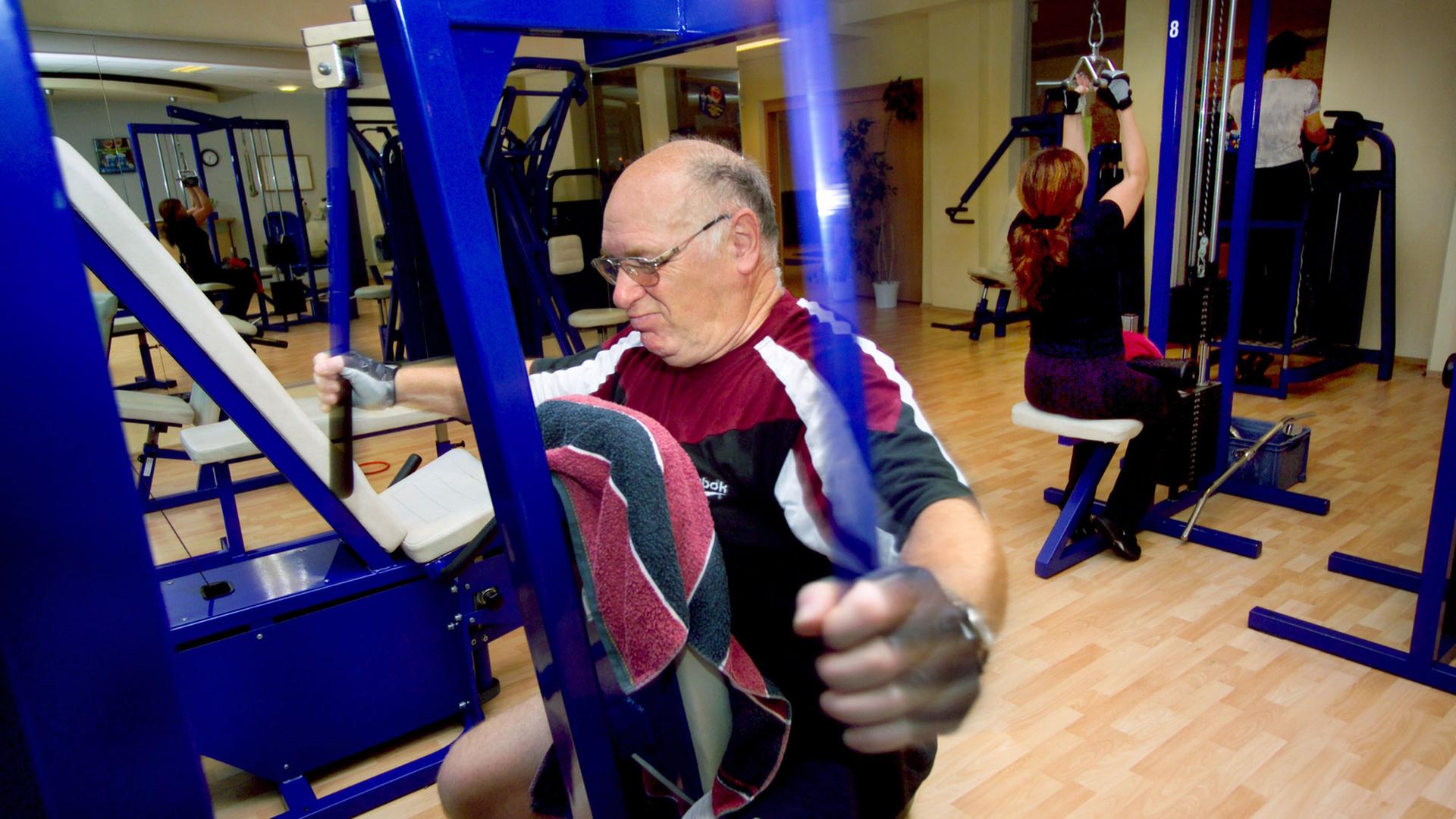 Ein älterer Mann beim ausgiebigen Training der Arme an einem speziellen Trainingsgerät. Ein älterer Mann beim ausgiebigen Training der Arme an einem speziellen Trainingsgerät.