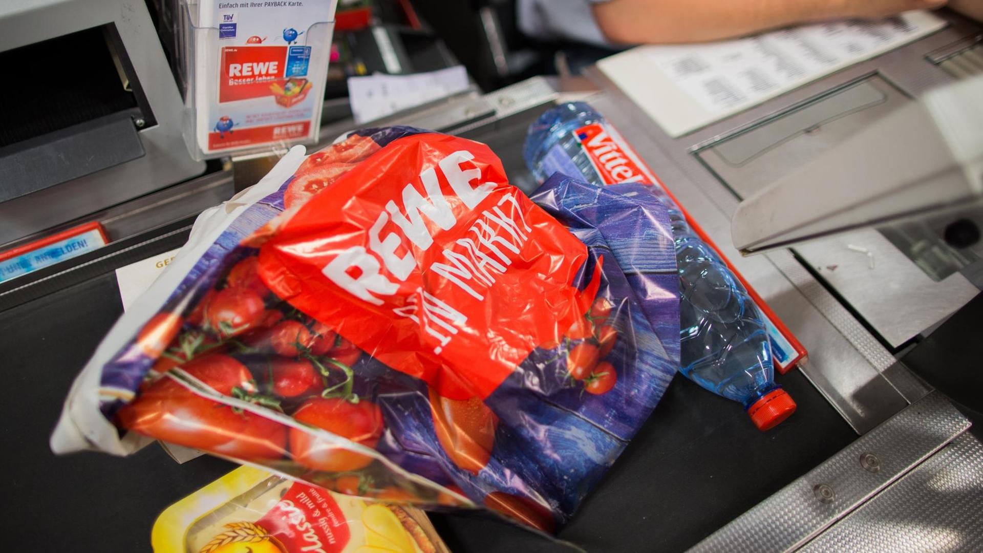 Eine Plastiktüte liegt an der Kasse eines Rewe-Marktes in Düsseldorf auf einem Laufband. Eine Plastiktüte liegt an der Kasse eines Rewe-Marktes in Düsseldorf auf einem Laufband.