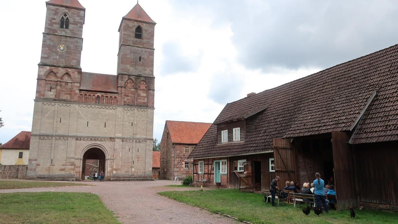 Blick auf die Klosterruine mit Scheune in und vor der Menschen an einem Vortrag teilnehmen Blick auf die Klosterruine mit Scheune in und vor der Menschen an einem Vortrag teilnehmen