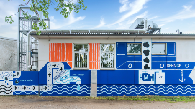 Ein Graffiti an der Außenwand des Großmaschinenlabor des Maritimen Zentrums der Hochschule Flensburg zeigt den Aufbau des deutschlandweit einzigartigen Versuchsstands zur Reinigung von Schiffsabgasen