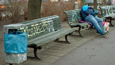 Ein Obdachloser schläft in Berlin auf einer Parkbank