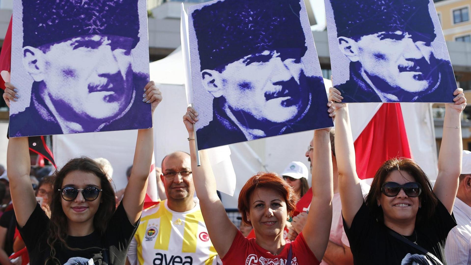 Drei Frauen halten Porträts von Staatsgründer Atatürk in die Luft. Drei Frauen halten Porträts von Staatsgründer Atatürk in die Luft.