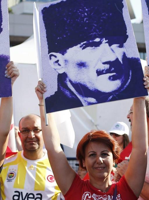 Drei Frauen halten Porträts von Staatsgründer Atatürk in die Luft.