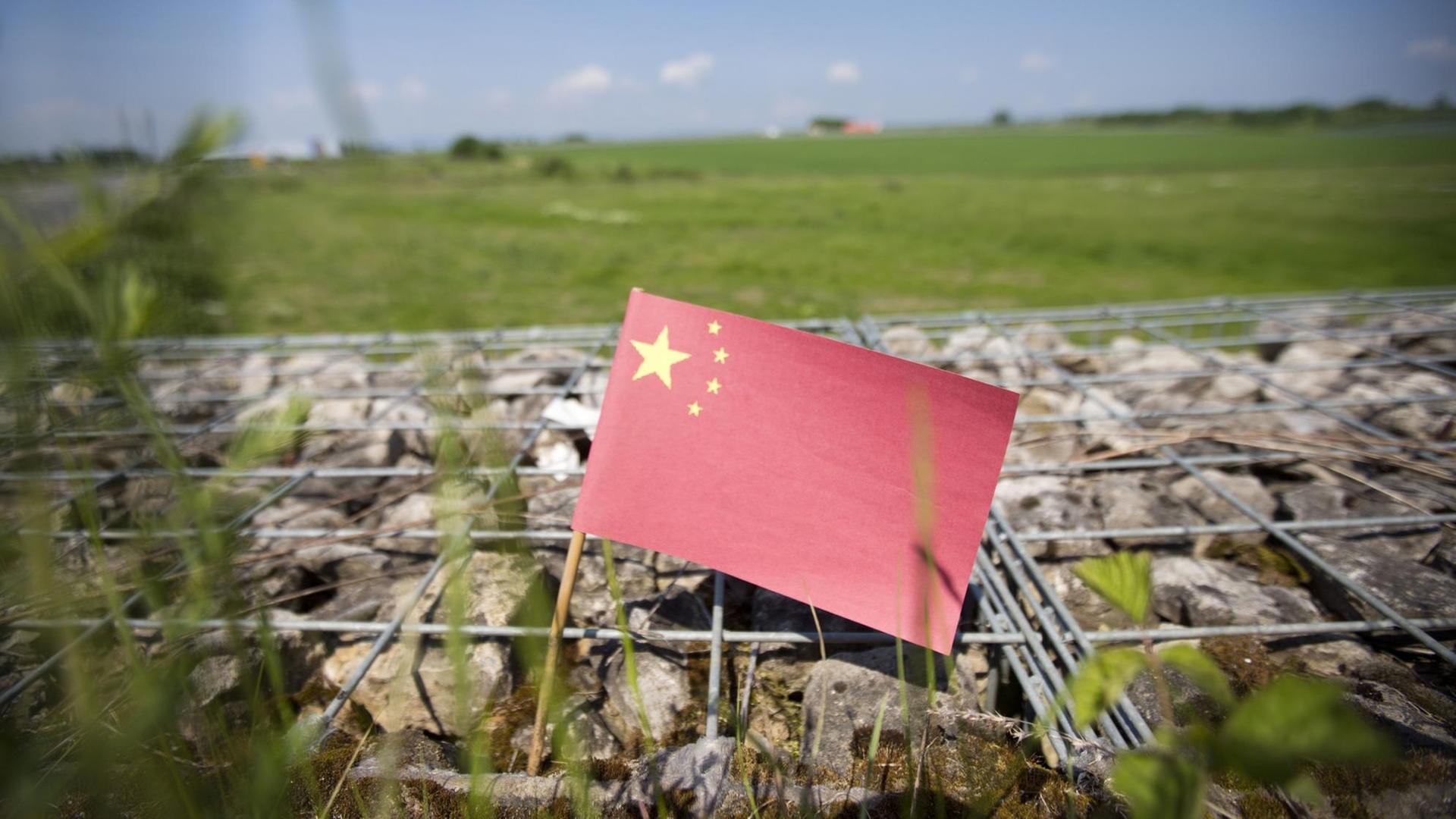 Eine kleine chinesische Fahne weht vor einem Feld in einem geplanten Gewerbegebiet in Bad Vilbel (Symbolbild). Nach einem Bericht der Frankfurter Rundschau verhandelt die Kommune am Rande von Frankfurt am Main über die größte Investition Chinas in Deutschland. Für etwa 700 Millionen Euro könnte im Gewerbegebiet "Quellenpark" ein chinesisches Handelszentrum entstehen. Eine kleine chinesische Fahne weht vor einem Feld in einem geplanten Gewerbegebiet in Bad Vilbel (Symbolbild). Nach einem Bericht der Frankfurter Rundschau verhandelt die Kommune am Rande von Frankfurt am Main über die größte Investition Chinas in Deutschland. Für etwa 700 Millionen Euro könnte im Gewerbegebiet "Quellenpark" ein chinesisches Handelszentrum entstehen.