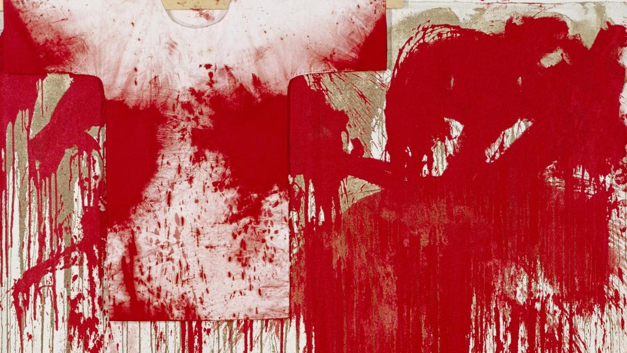 Auf einer Leinwand hängt ein weißes Hemd. Die gesamte Leinwand, wie auch das Hemd sind über und über mit roter Farbe bespritzt. Es mutet an wie Blut. Auf einer Leinwand hängt ein weißes Hemd. Die gesamte Leinwand, wie auch das Hemd sind über und über mit roter Farbe bespritzt. Es mutet an wie Blut.