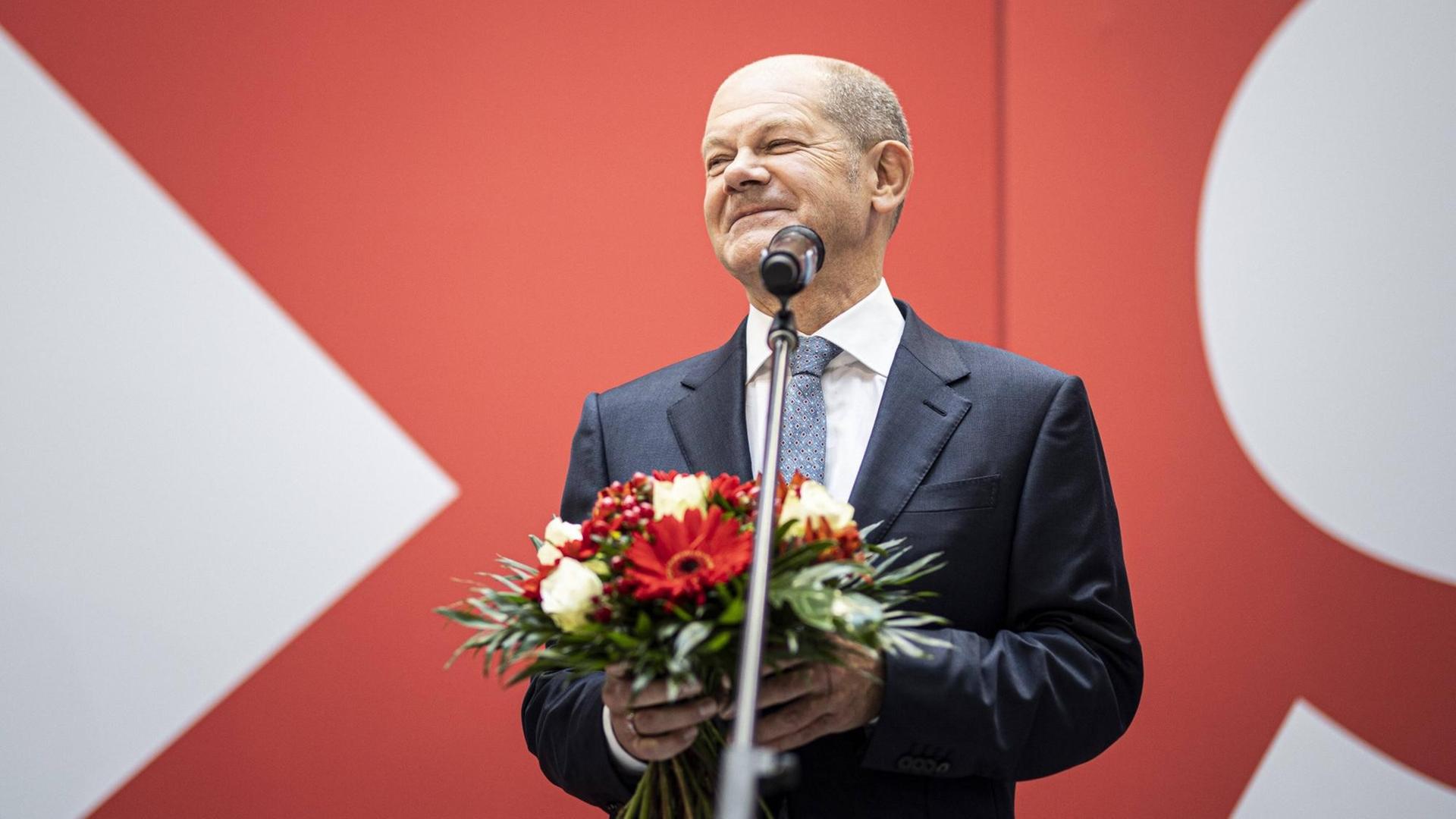 Olaf Scholz, Kanzlerkandidat der SPD, hält einen Blumenstrauß in der Hand und lächelt.