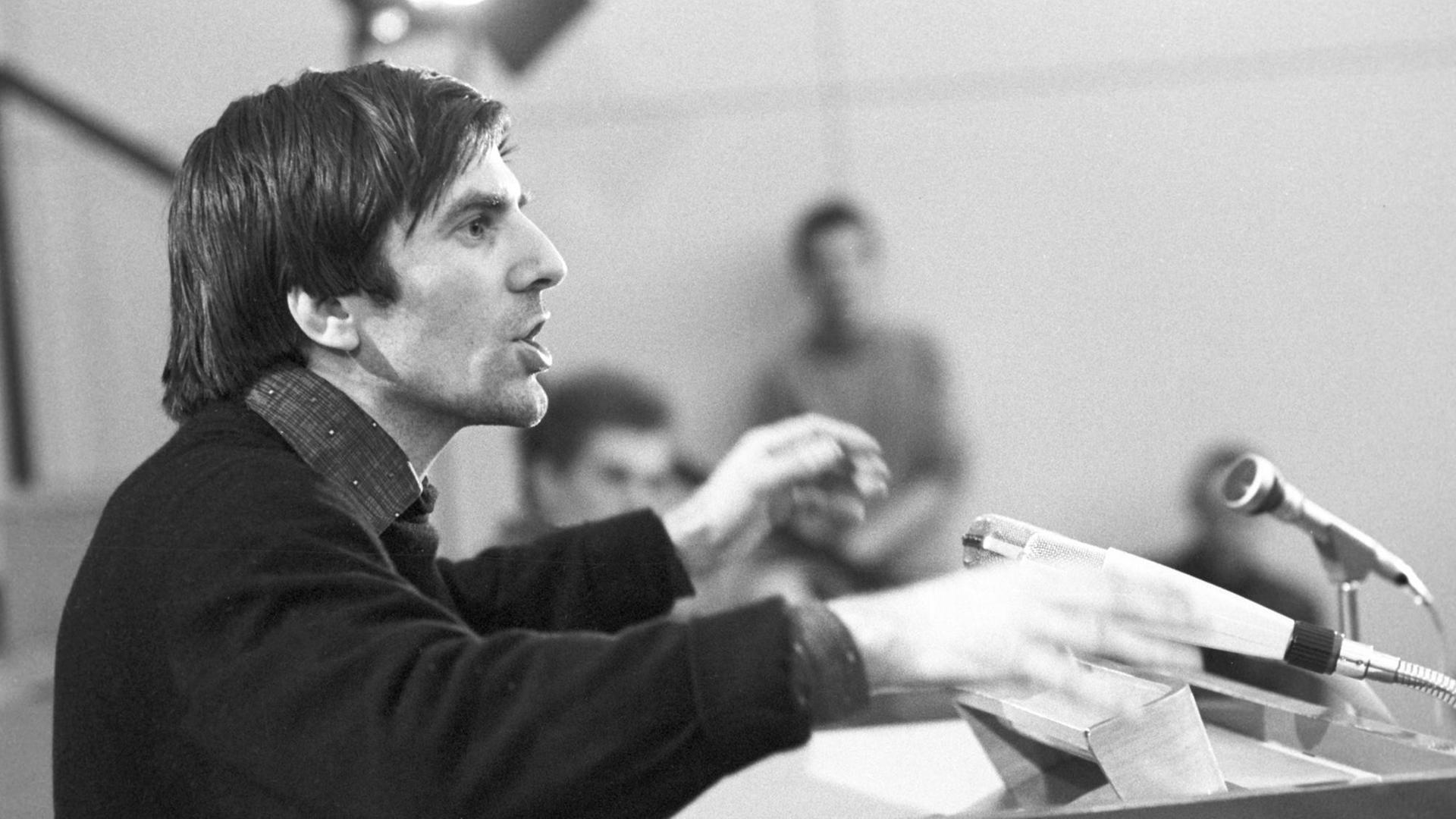 Studentenführer Rudi Dutsche steht während eines Vortrags in der Aula der Halenpaghenschule in Buxtehude am 06.03.1968 an einem Rednerpult und spricht Studentenführer Rudi Dutsche steht während eines Vortrags in der Aula der Halenpaghenschule in Buxtehude am 06.03.1968 an einem Rednerpult und spricht