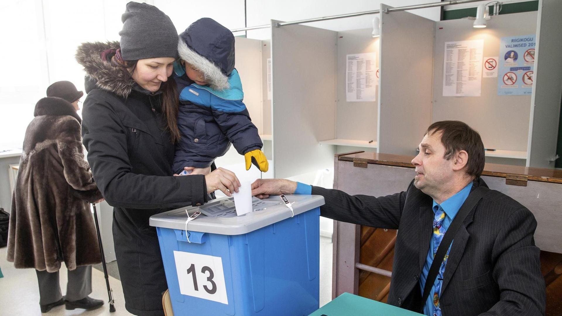 Eine Frau mit einem Kind auf dem Arm wirft in Tallinn ihren Wahlzettel in eine Urne. Eine Frau mit einem Kind auf dem Arm wirft in Tallinn ihren Wahlzettel in eine Urne.