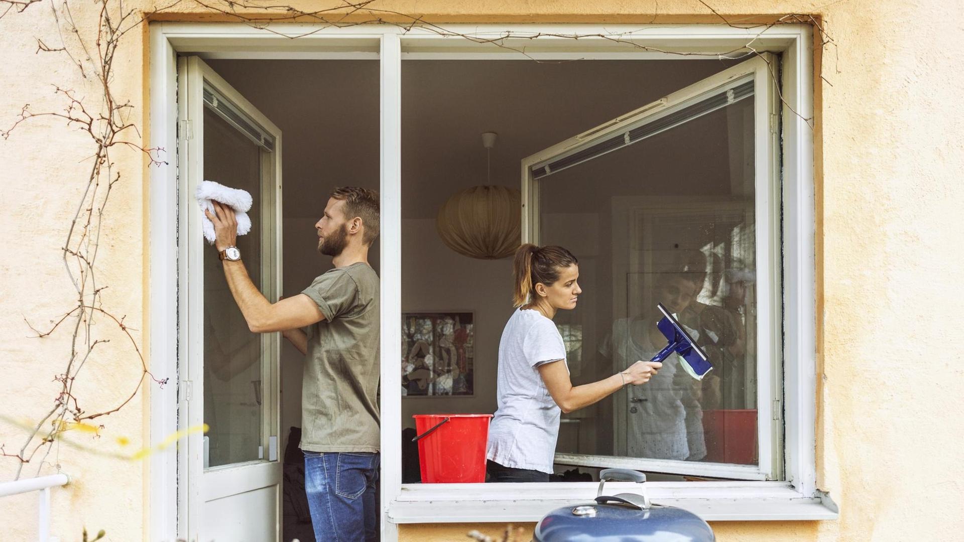 Ein Mann und eine Frau putzen gemeinsam die Fenster. Ein Mann und eine Frau putzen gemeinsam die Fenster.