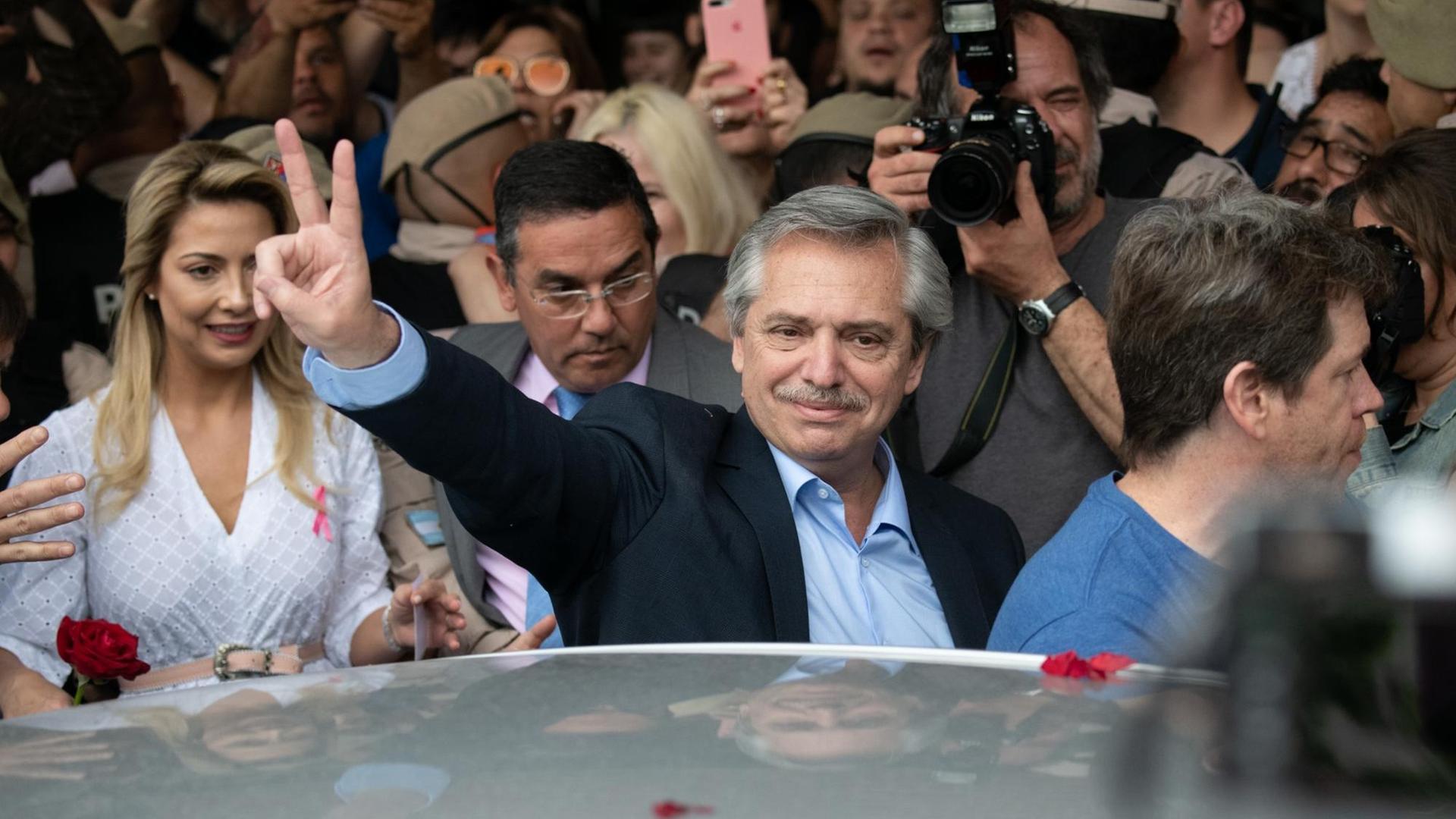 Alberto Ángel Fernández, Präsidentschaftskanidat des Parteienbündnisses Frente de Todos in Argentiien spreizt nach seiner Stimmangabe in Buenos Aires die Finger einer Hand. Links steht seine Frau. | Verwendung weltweit