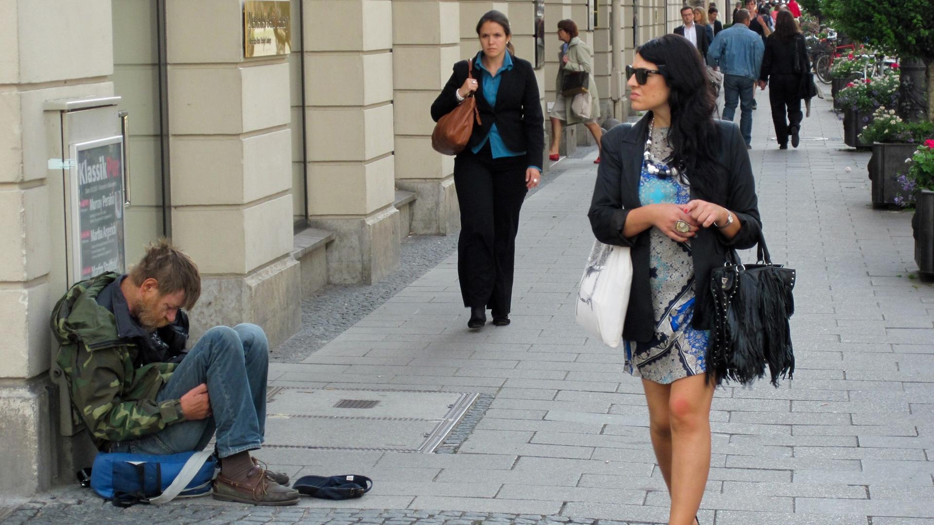 Eine Frau mit Sonnenbrille läuft vorbei an einem Bettler in der Brienner Straße in der Münchner Innenstadt. Eine Frau mit Sonnenbrille läuft vorbei an einem Bettler in der Brienner Straße in der Münchner Innenstadt.