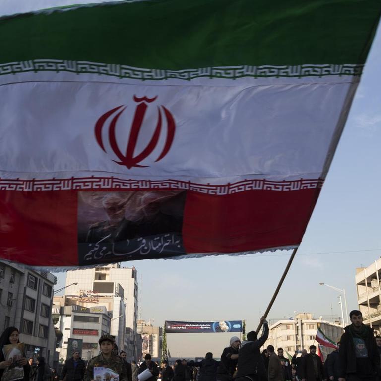 Menschen und eine iranische Flagge sind auf den Straßen Tehrans am 6. Januar bei der Beerdigung des iranischen Generals Qasem Soleimani zu sehen. 