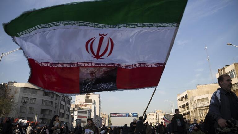 Menschen und eine iranische Flagge sind auf den Straßen Tehrans am 6. Januar bei der Beerdigung des iranischen Generals Qasem Soleimani zu sehen. 