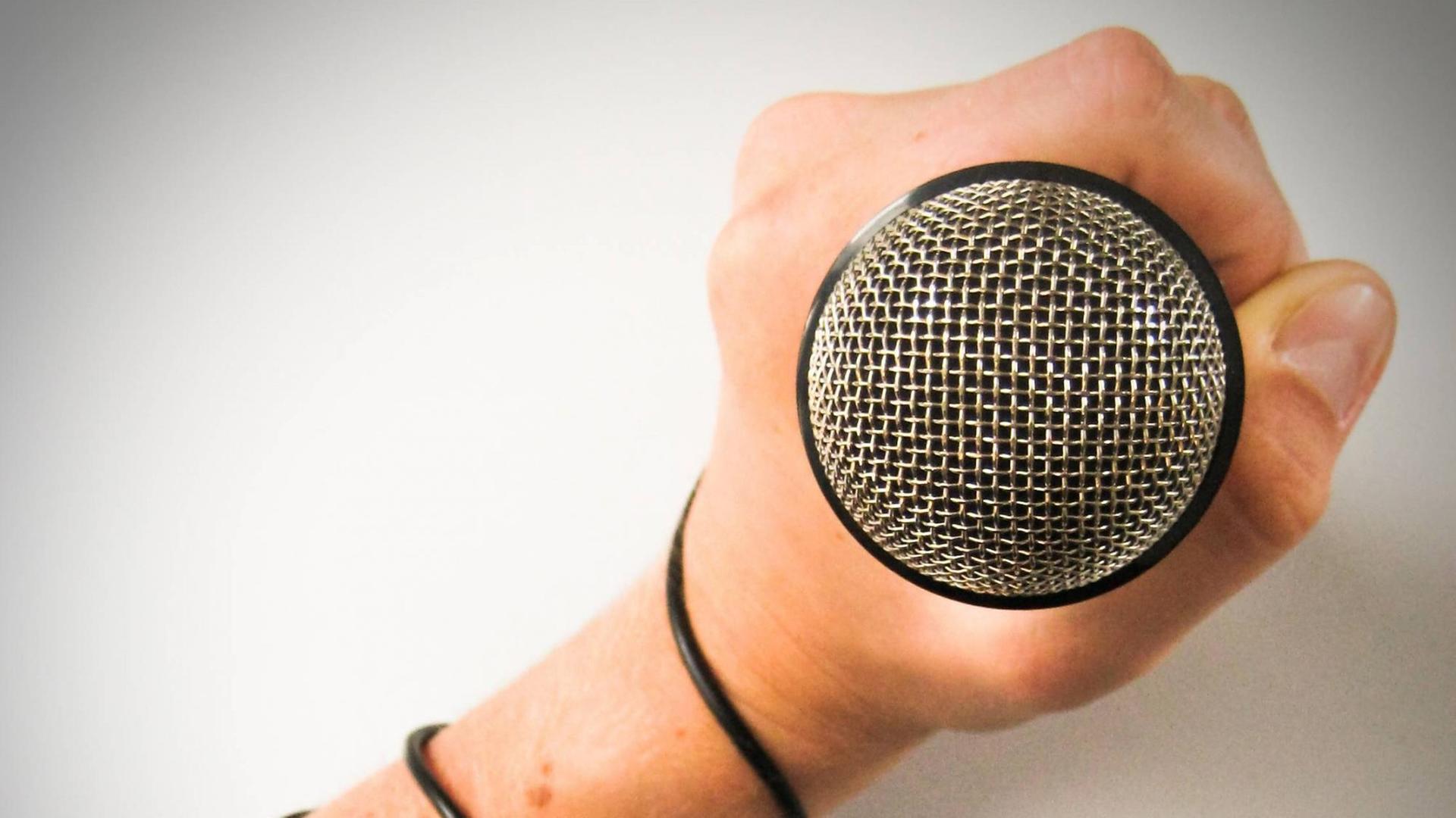 Eine Hand hält ein Mikrofon Eine Hand hält ein Mikrofon
