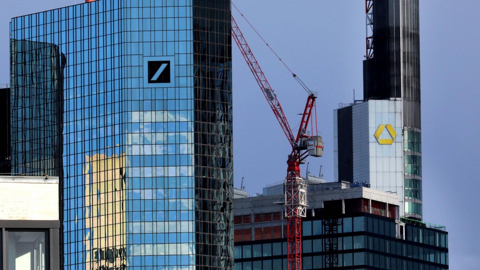 Die Türme der Deutschen Bank und der Commerzbank mit ihrem jeweiligen Logo. Davor ein Baukran. Die Türme der Deutschen Bank und der Commerzbank mit ihrem jeweiligen Logo. Davor ein Baukran.