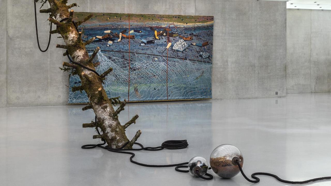 Ein Baumstamm ragt ins zweite Obergeschoss des Kunsthauses Bregenz. Um ihn herum gebunden sind Miniaturgewächshäuser in salatschüsselgroßen Glaskugeln. Ein Baumstamm ragt ins zweite Obergeschoss des Kunsthauses Bregenz. Um ihn herum gebunden sind Miniaturgewächshäuser in salatschüsselgroßen Glaskugeln.