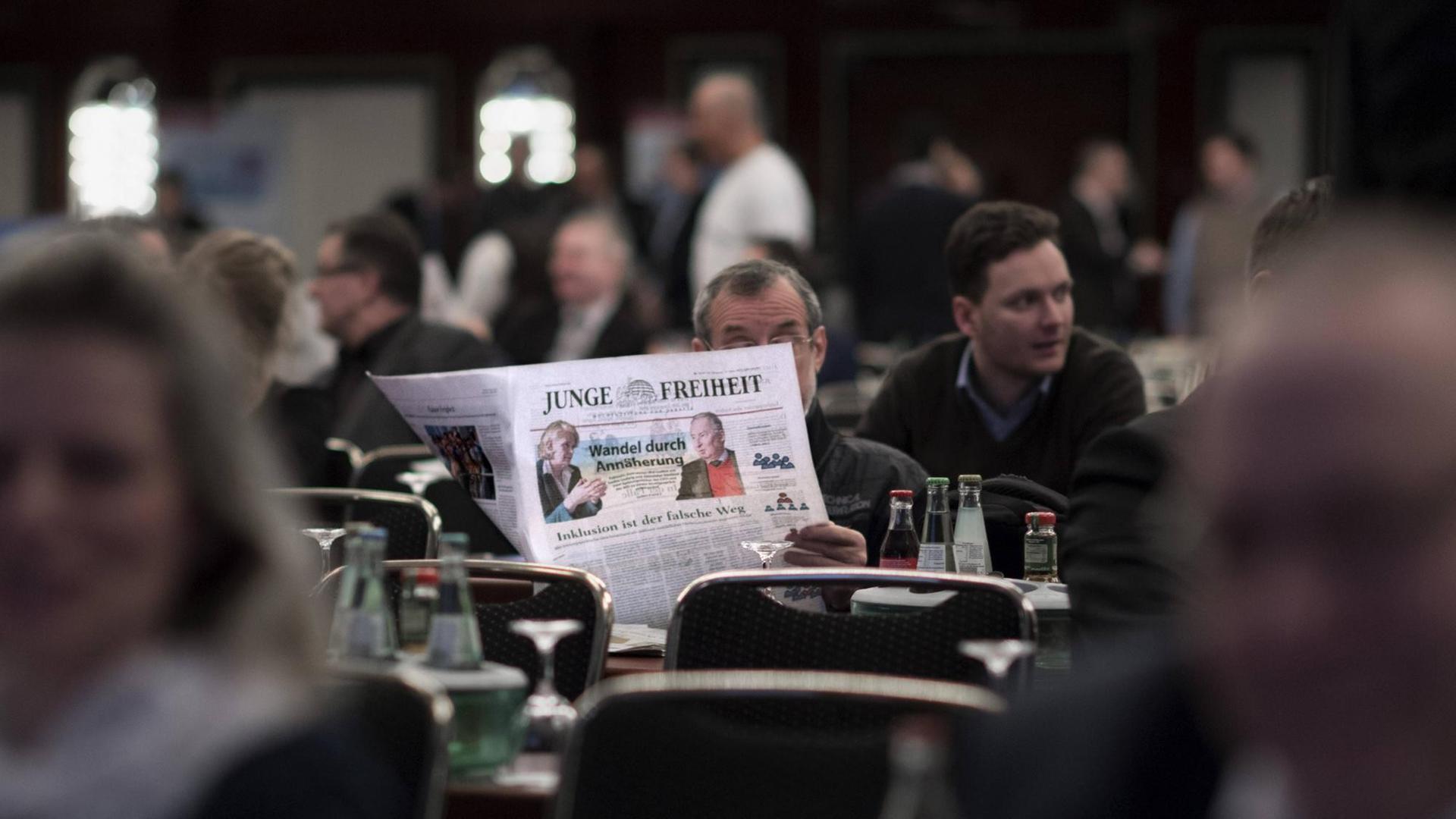 Ein Mann sitzt an einem Tisch und liest die Zeitung "Junge Freiheit". Ein Mann sitzt an einem Tisch und liest die Zeitung "Junge Freiheit".