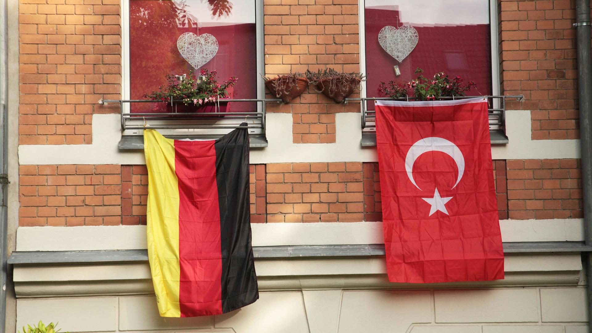 Eine rote, türkische Fahne mit dem Halbmond und dem Stern hängt während der Fußball-EM 2016 in Berlin an einem Haus neben der deutschen Flagge in Schwarz-Rot-Gold. Eine rote, türkische Fahne mit dem Halbmond und dem Stern hängt während der Fußball-EM 2016 in Berlin an einem Haus neben der deutschen Flagge in Schwarz-Rot-Gold.