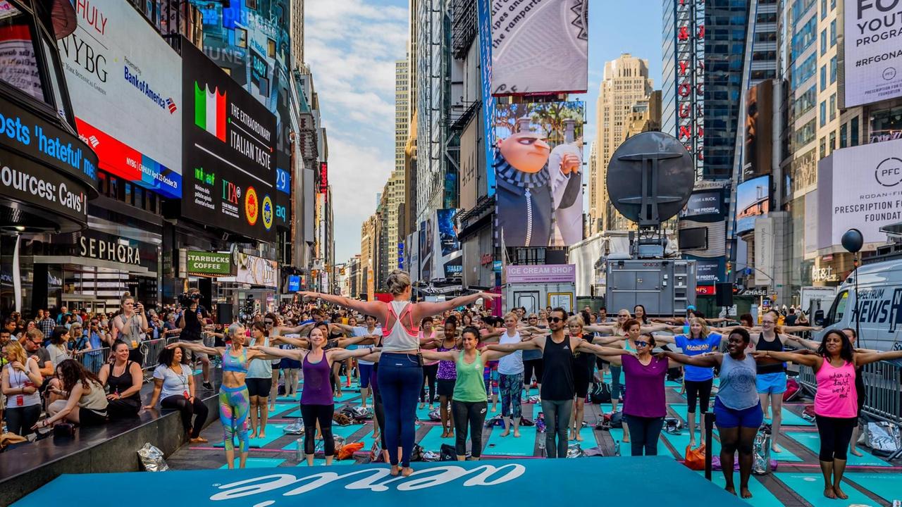 Teilnehmer einer öffentlichen Yogastunde auf dem Times Square in New York City. Teilnehmer einer öffentlichen Yogastunde auf dem Times Square in New York City.