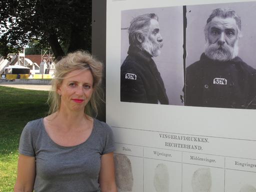 Die niederländische Journalistin Suzanna Jansen vor dem Porträt ihres Urgroßvaters im Innenhof der Besserungsanstalt Veenhuizen, die heute ein Museum ist.
